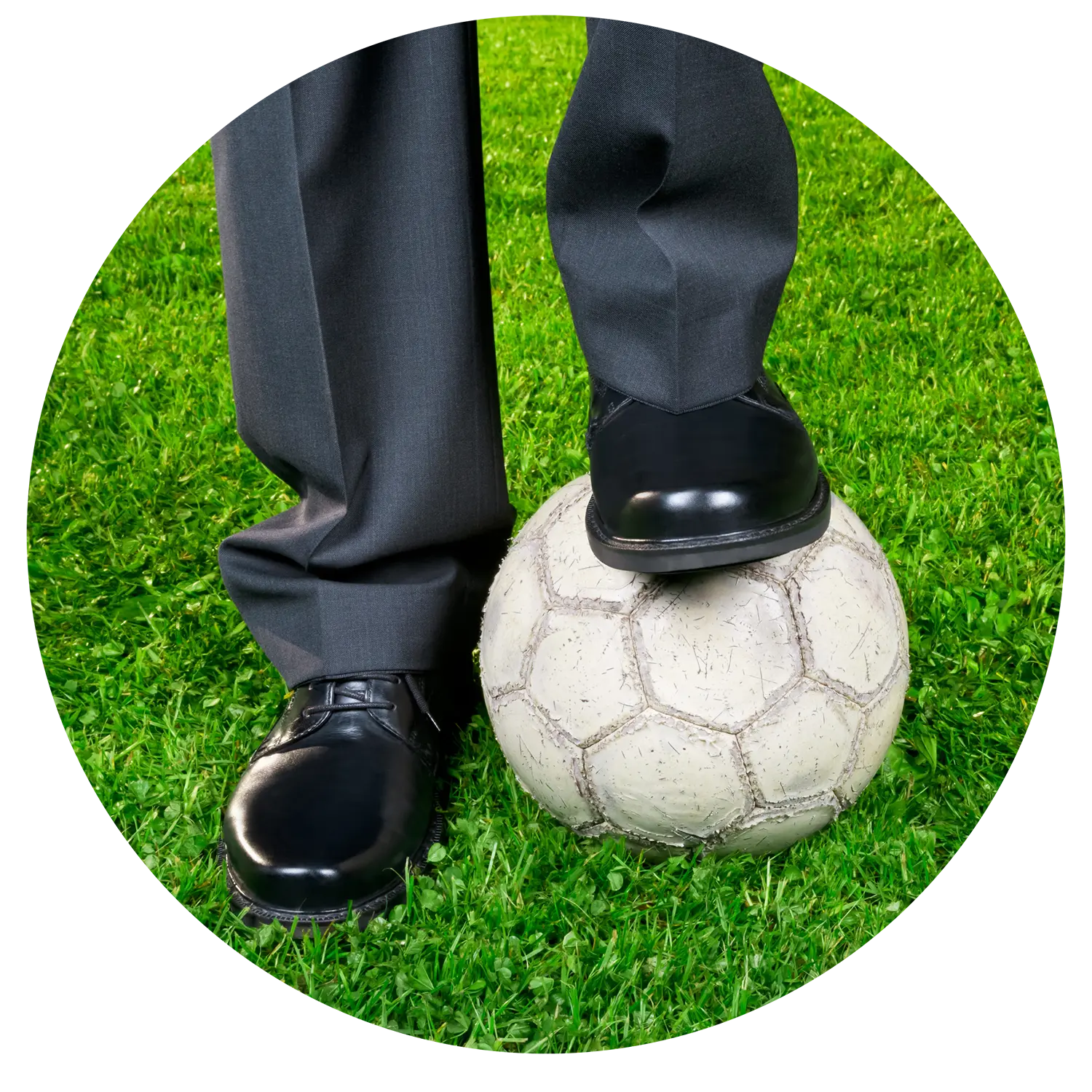 Image of a businessman's legs and feet in a suit and shoes with one leg resting on a soccer ball.