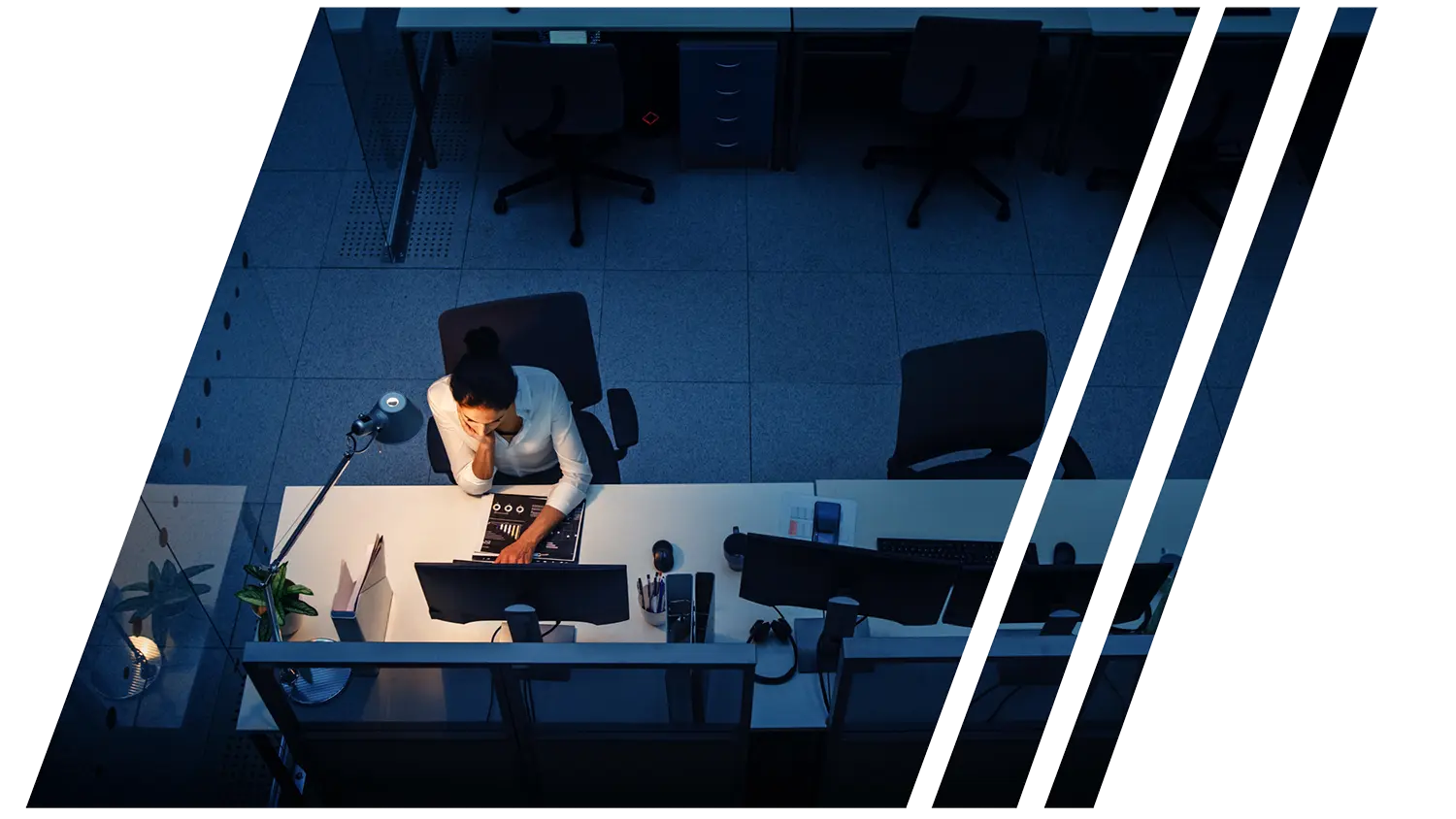 Image of a woman sitting in a dark office alone at her computer representing small businesses trying to do everything alone.