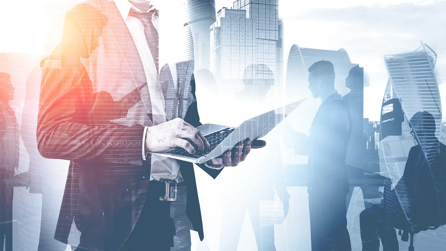 Image of a businessman typing on a laptop with business people and buildings in the background.